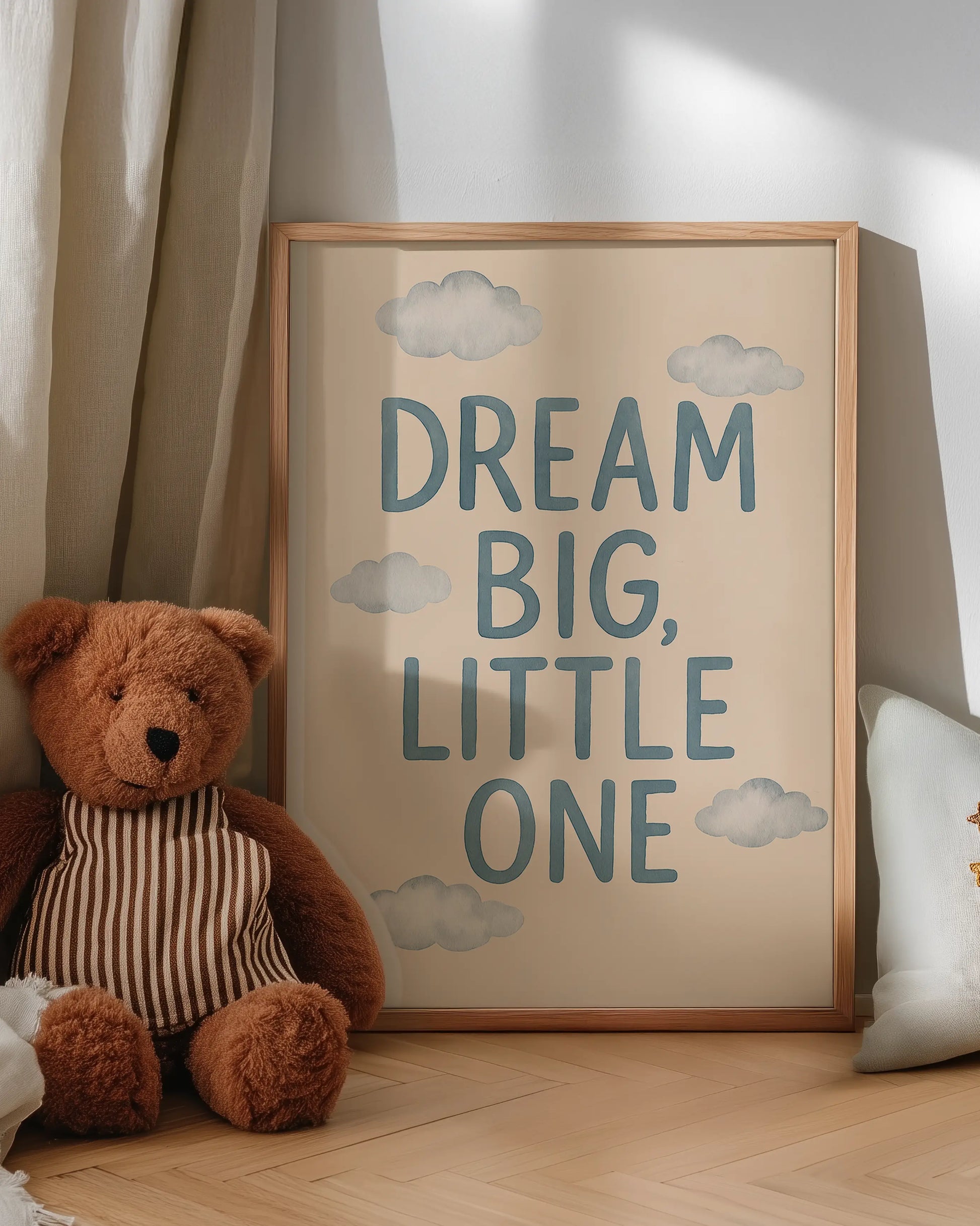 Framed artwork with 'Dream Big, Little One' text next to a teddy bear on a wooden floor.