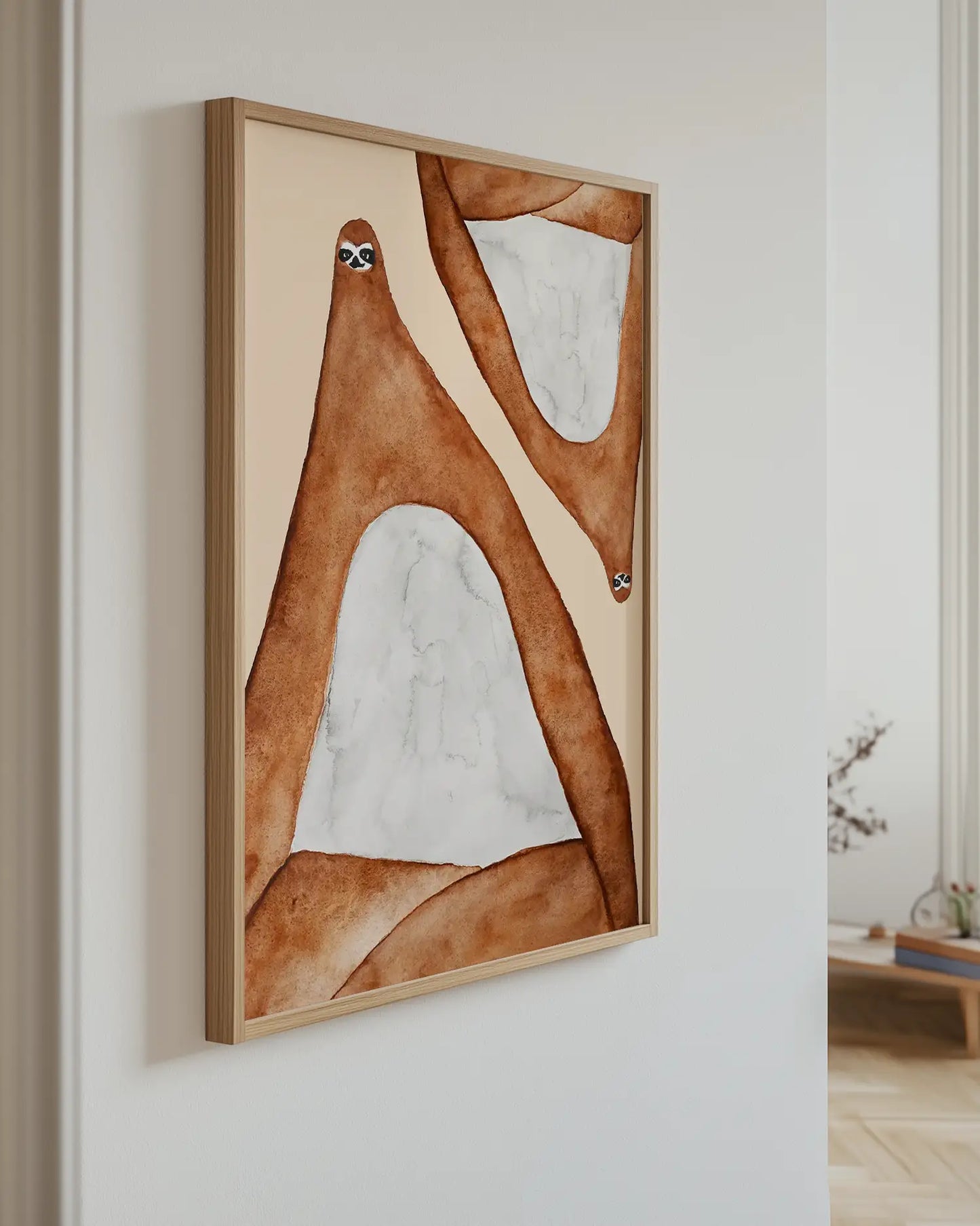 Art piece with two lazy sloths in brown and beige tones on a white wall