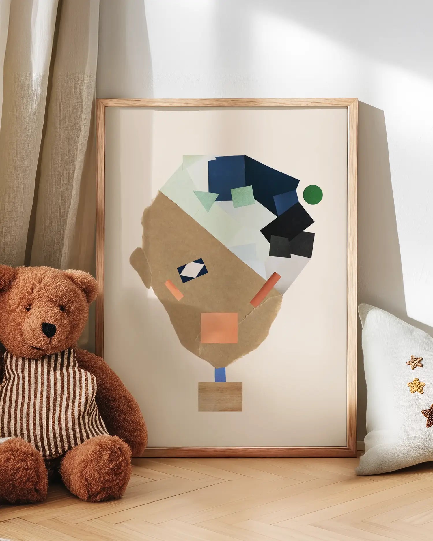 Framed abstract art piece of a collage face on a wall with a teddy bear and decorative pillow.