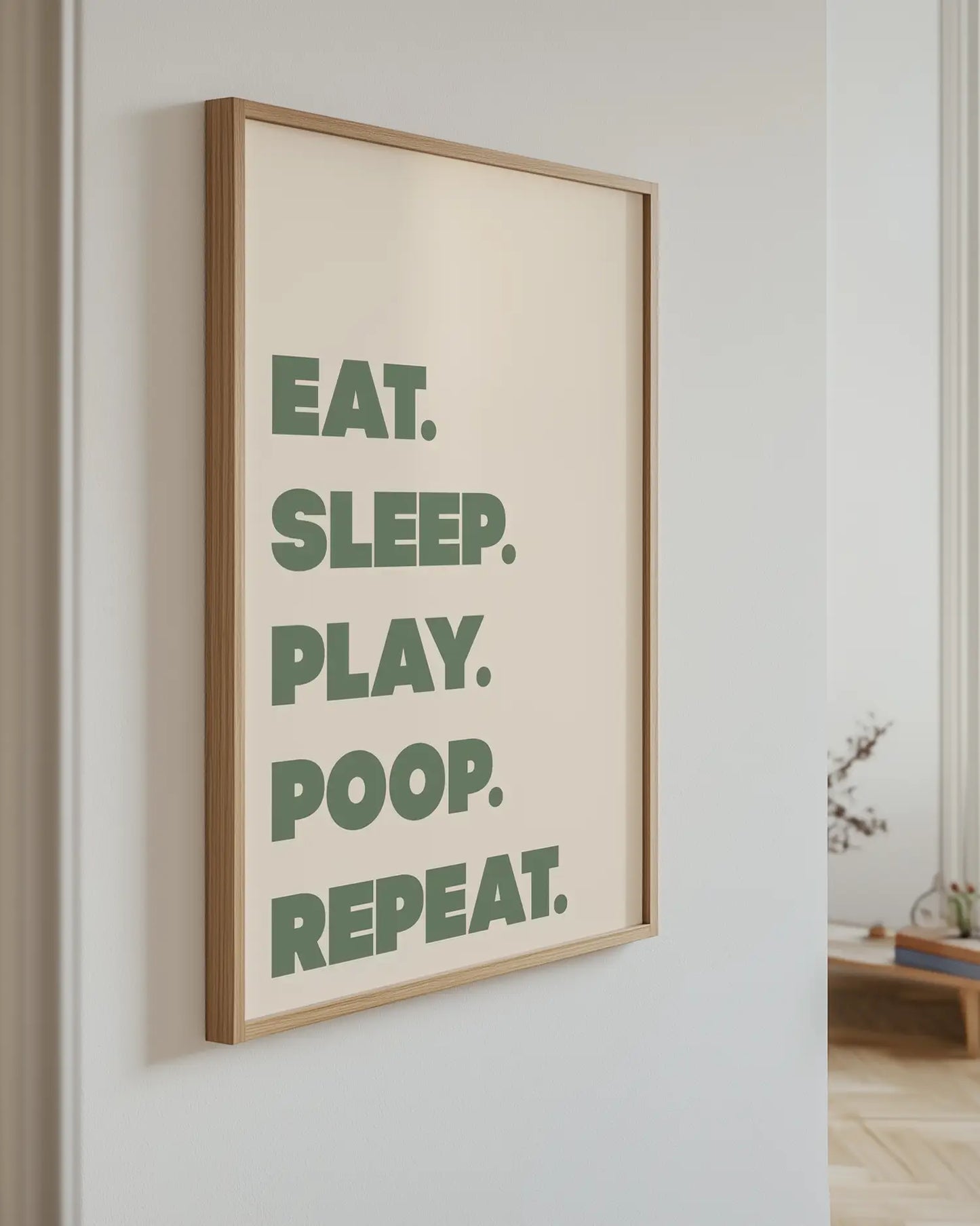 Framed poster with motivational quote 'EAT. SLEEP. PLAY. POOP. REPEAT.' on a wall.