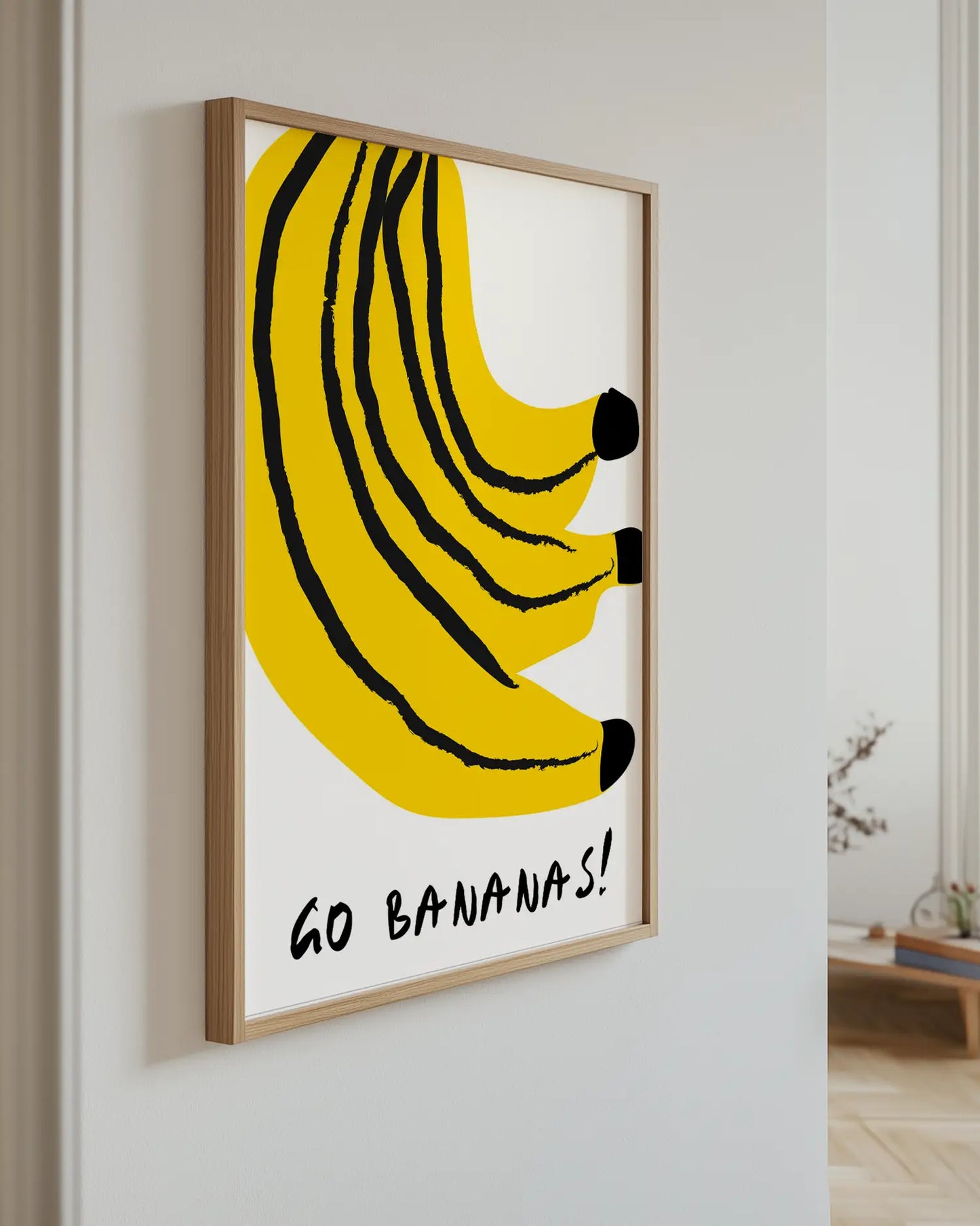 Framed artwork of bananas with 'GO BANANAS!' text on a white wall.