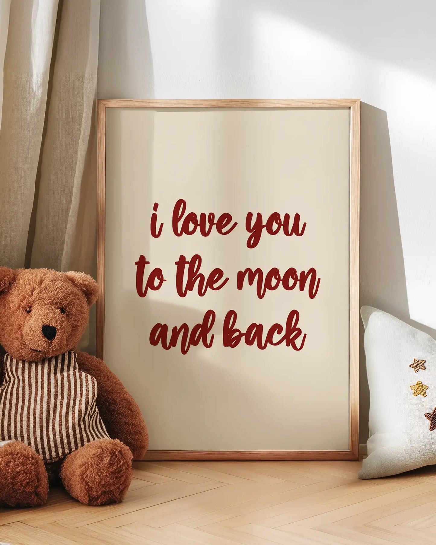 Poster with 'I love you to the moon and back' text next to a teddy bear on a wooden floor.