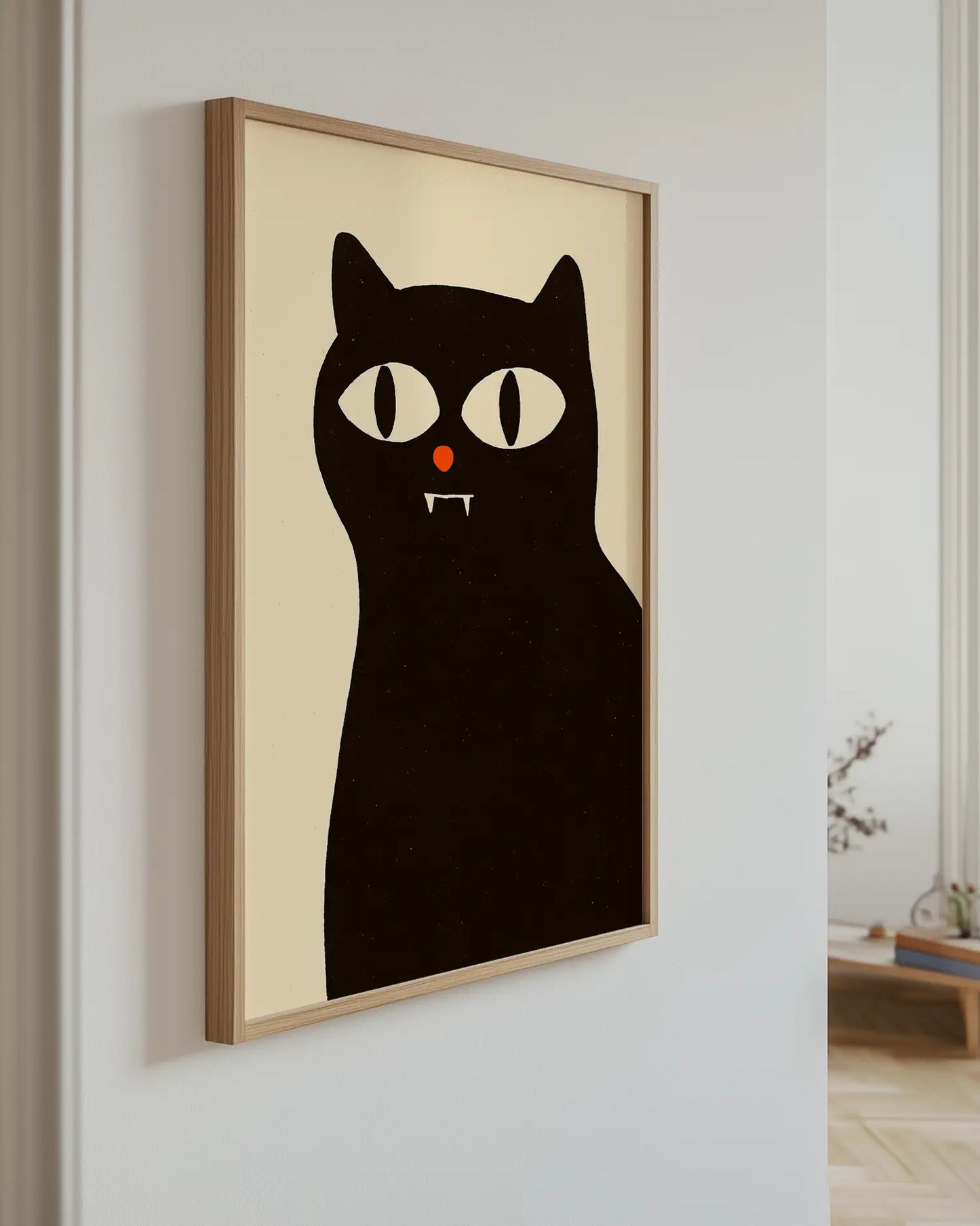 Framed artwork of a black cat with vampire teeth with a wooden frame on a white wall.