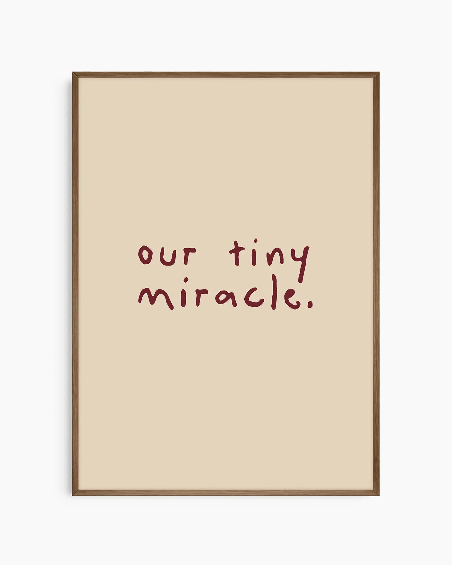 Beige nursery poster with 'our tiny miracle.' text in brown framed in a dark oak frame.