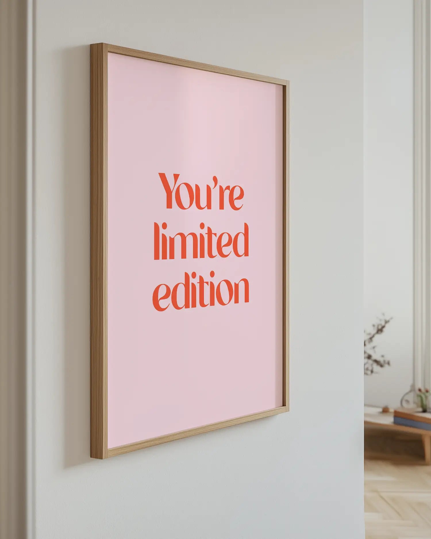 Artwork with 'You're limited edition' text on a pink background, mounted on a wall.