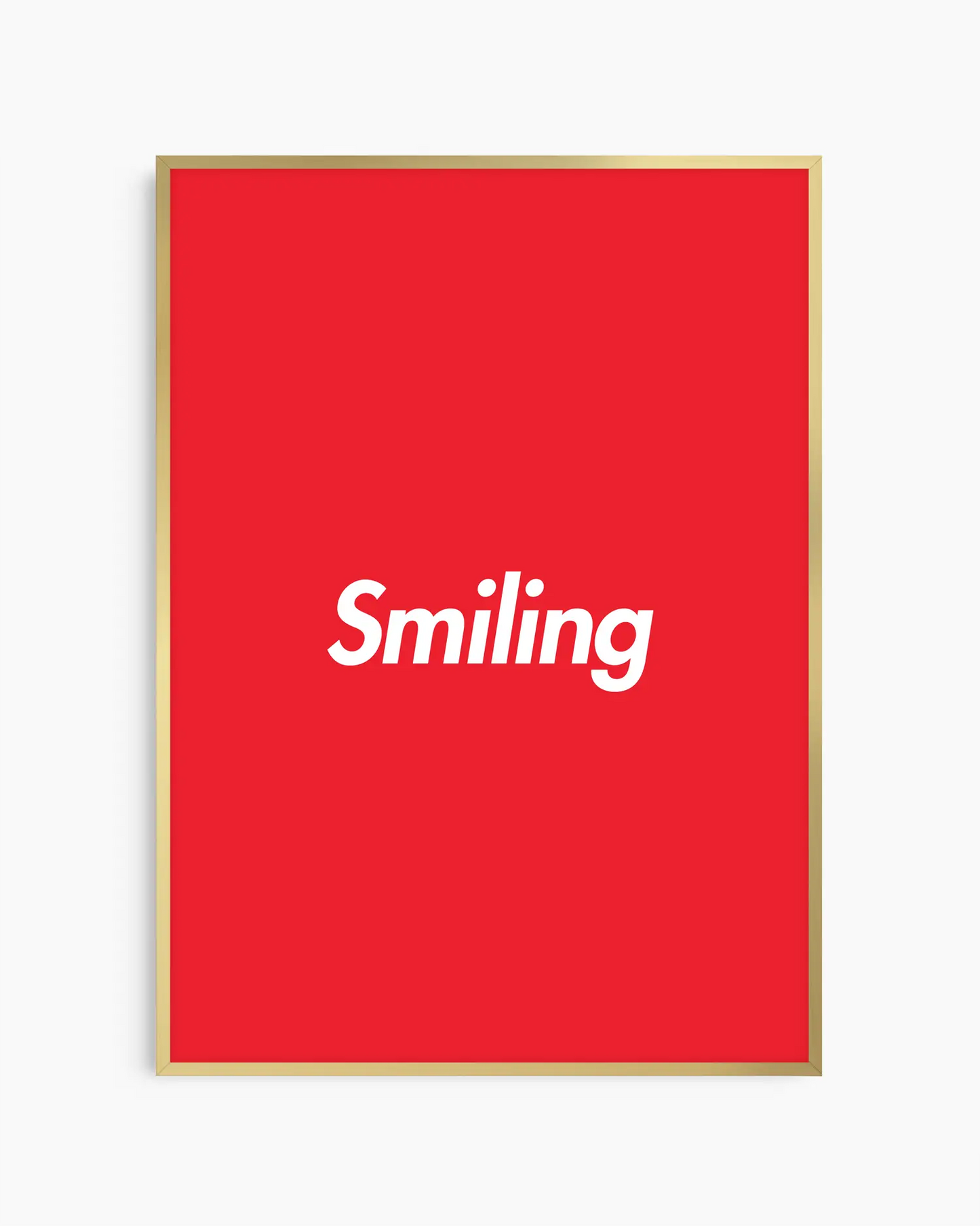 Red poster with 'Smiling' written in white, inserted in a golden aluminium frame.