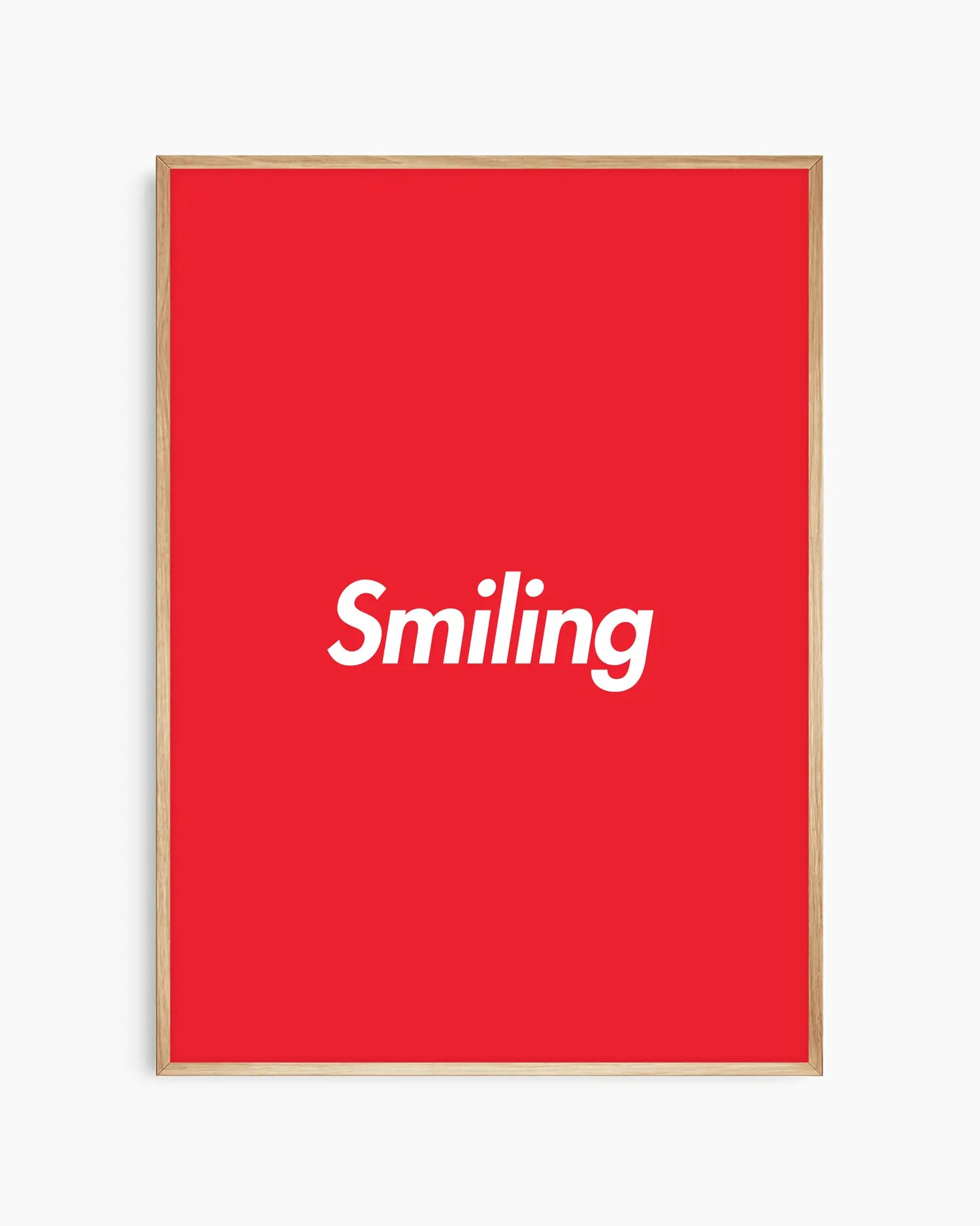 Red poster with 'Smiling' written in white, inserted in an oak frame.