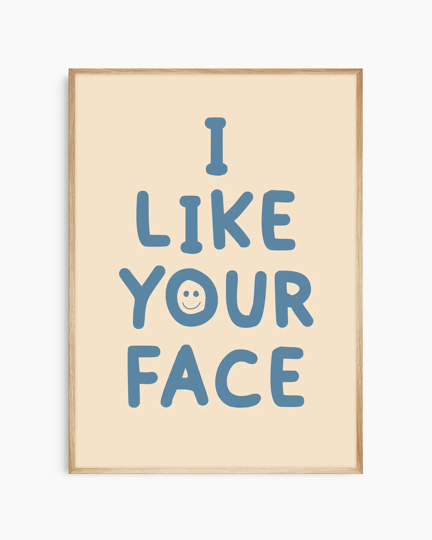 Beige nursery poster with the text 'I like your face' written in blue, framed in an oak frame.