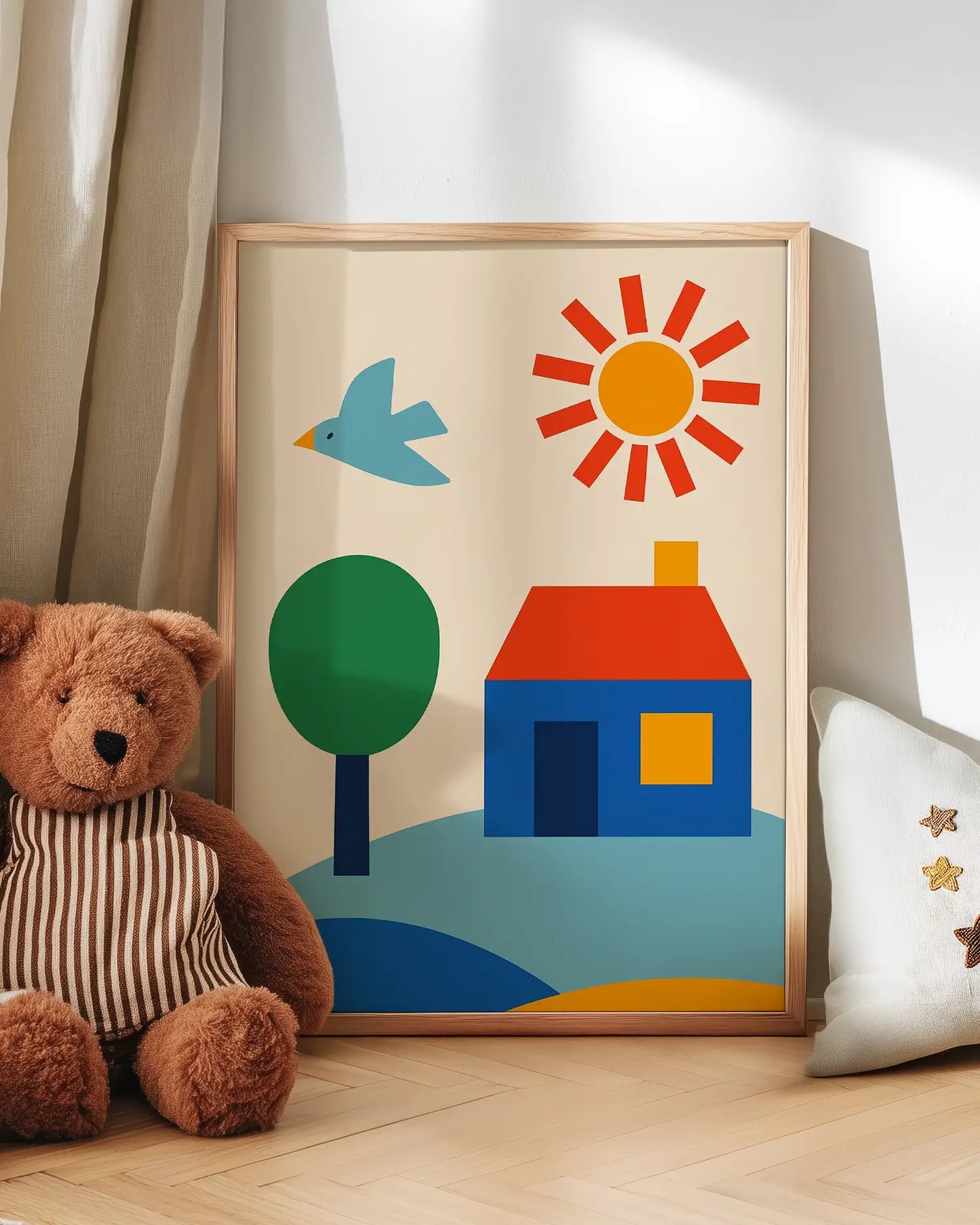Children's art with a house, sun, and tree next to a teddy bear on a wooden floor.