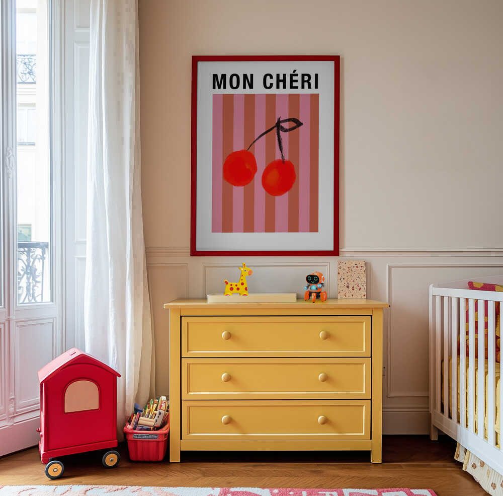 Nursery poster of two red cherries on a striped pink and orange background and the text 'MON CHÉRI' on top hanging on the wall