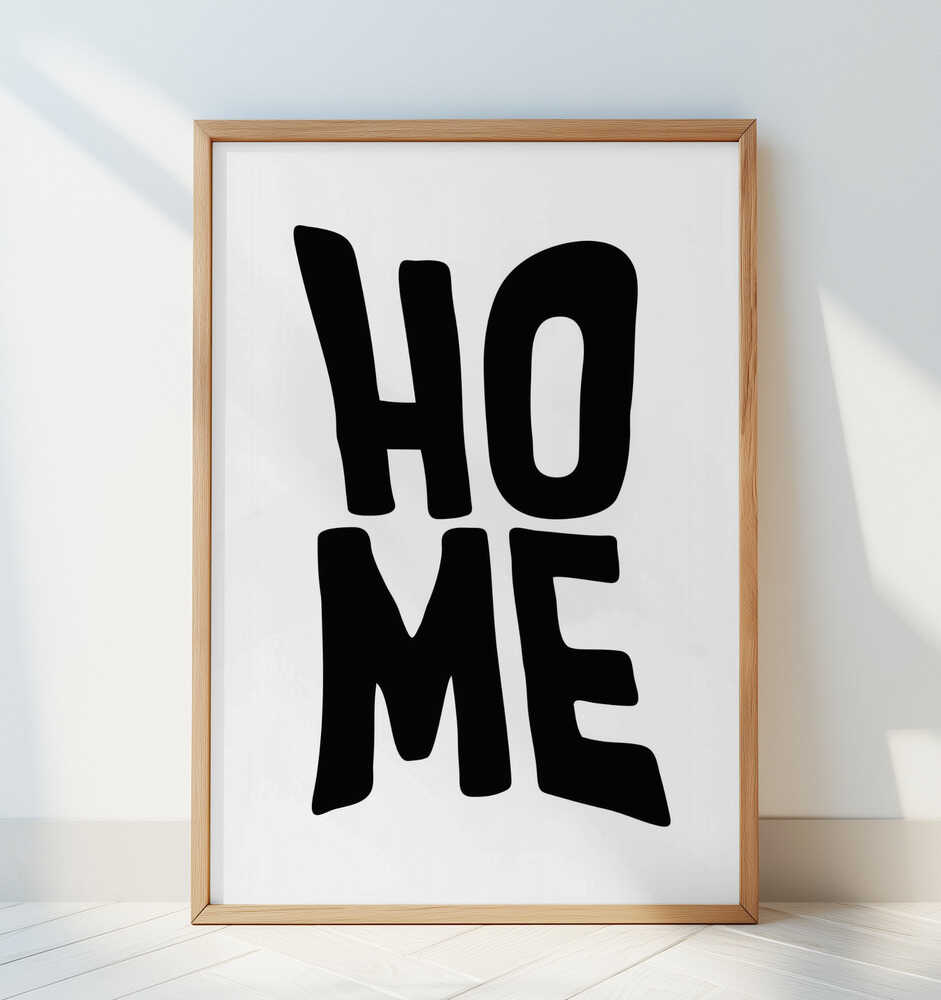 Framed nursery poster with the text 'HOME' written in black leaning against a white wall. 