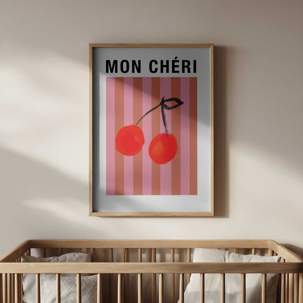 Nursery poster of two red cherries on a striped pink and orange background and the text 'MON CHÉRI' on top hanging above the crib